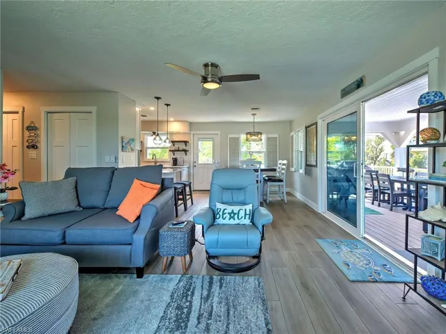 Living area with light wood-type flooring, a ceiling fan, and a textured ceiling