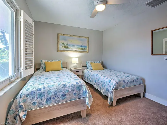 Carpeted bedroom with a ceiling fan and multiple windows