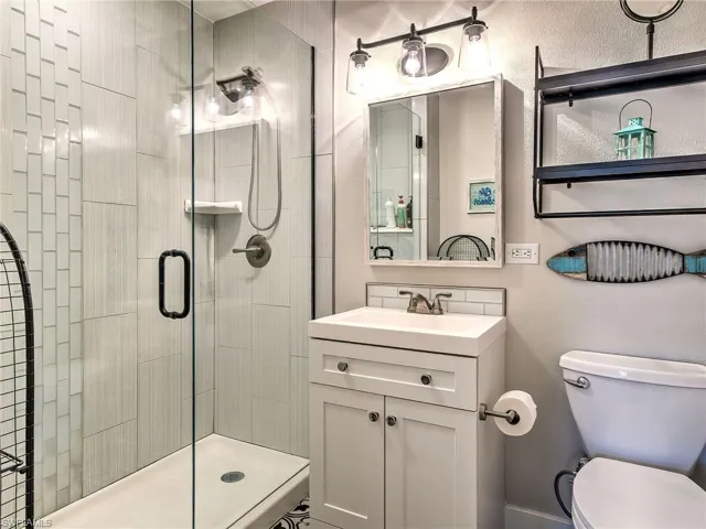 Full bath with a stall shower, vanity, and a textured wall