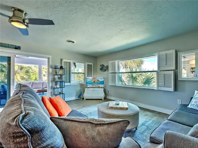 Living room featuring a textured ceiling, wood finished floors, and a ceiling fan