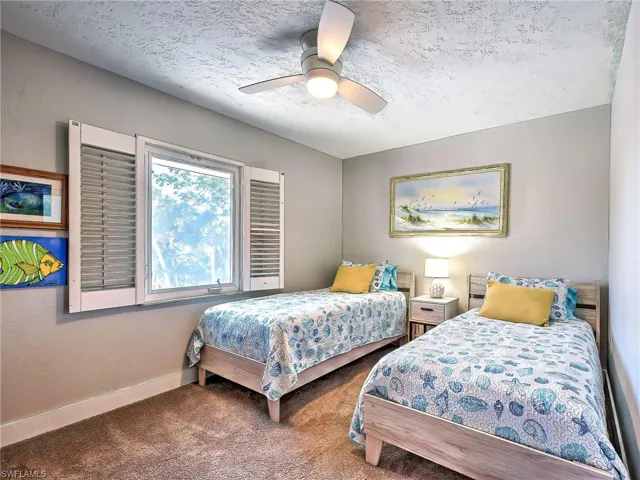 Carpeted bedroom with a ceiling fan and a textured ceiling