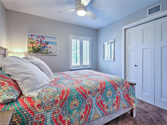 Carpeted bedroom featuring ceiling fan and a closet