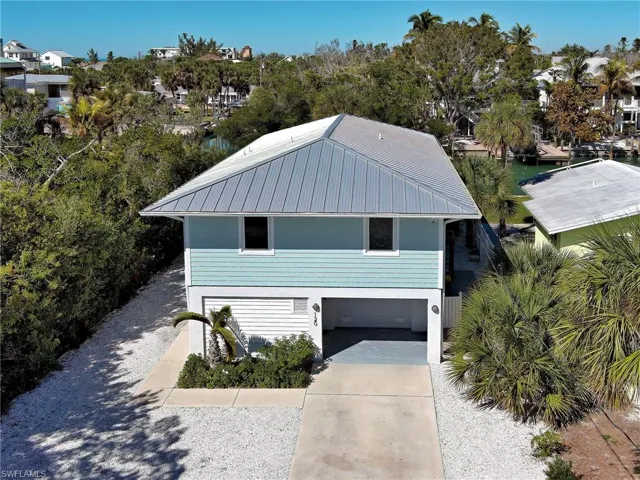 View of front of home featuring driveway, an attached garage, and a metal roof
