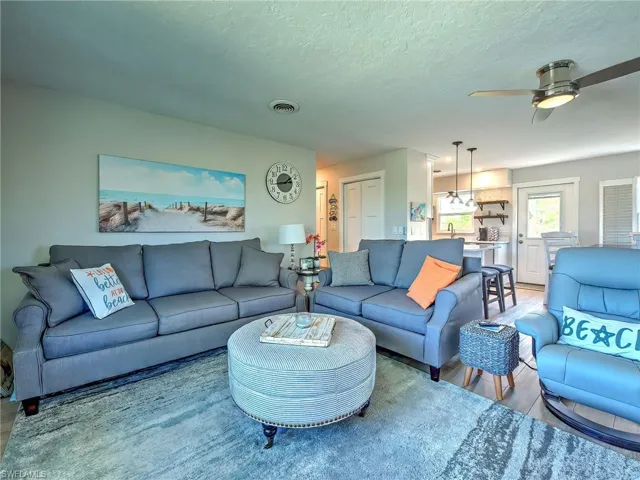 Living area with a ceiling fan, light wood-style flooring, and a textured ceiling