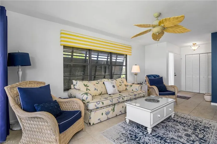 Living room with ceiling fan and light tile patterned flooring. End unit bonus windows!