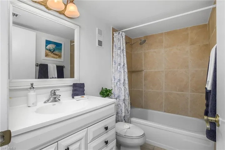 Guest bathroom with vanity, shower / tub combo, and toilet.