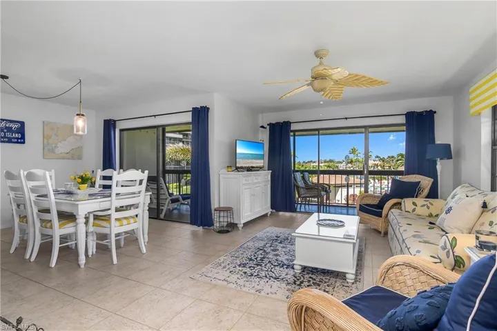 Living room with plenty of natural light, light tile patterned floors, and ceiling fan.