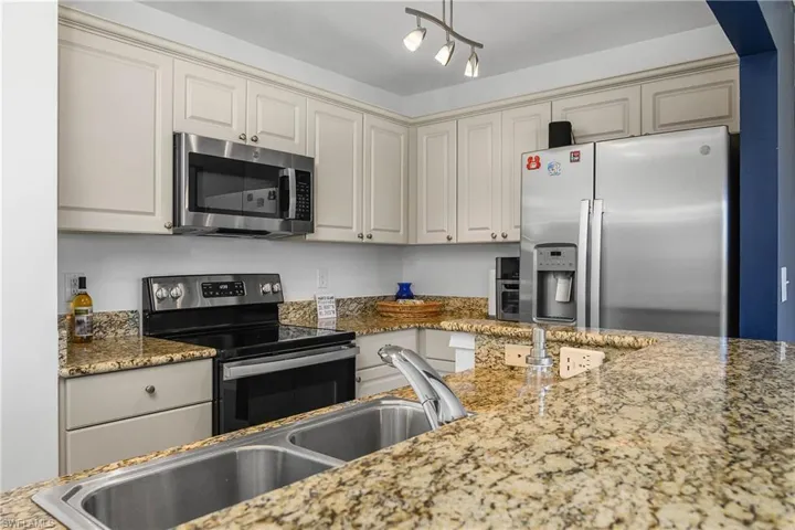 Kitchen featuring granite counters, sink, and appliances with stainless steel finishes.