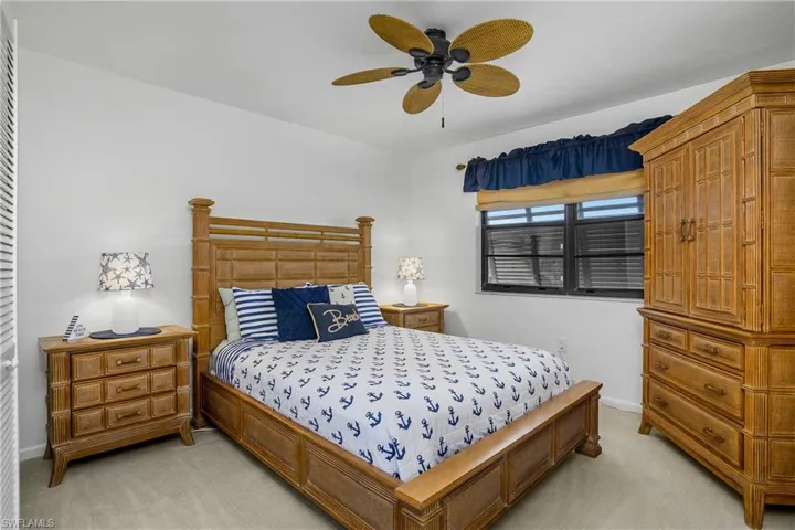 Guest bedroom carpeted floors with ceiling fan, decorative shutters.