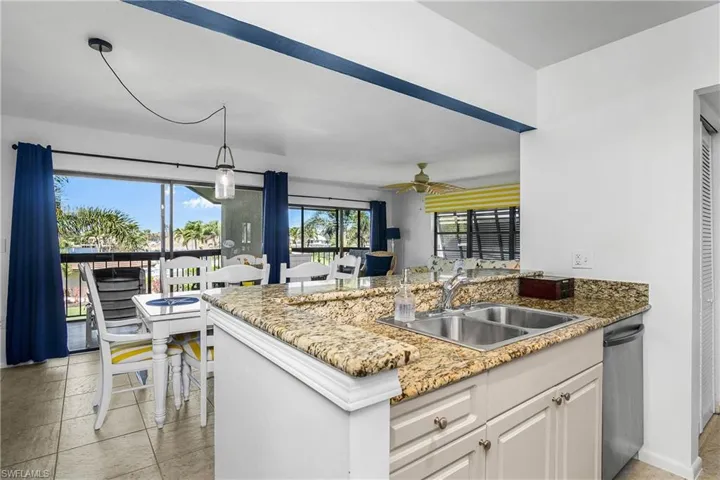 Kitchen featuring sink, dishwasher, hanging light fixtures, white cabinets, and kitchen peninsula.