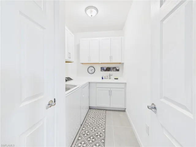 Laundry area featuring light tile patterned flooring, washer and clothes dryer, and cabinet space