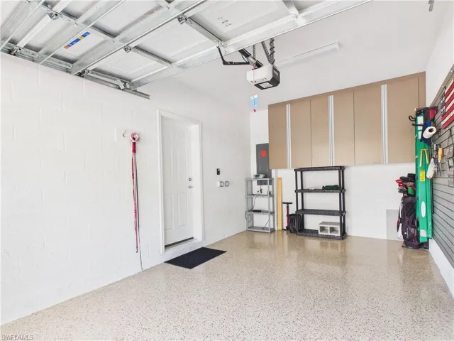 Garage with concrete block wall, electric panel, and a garage door opener