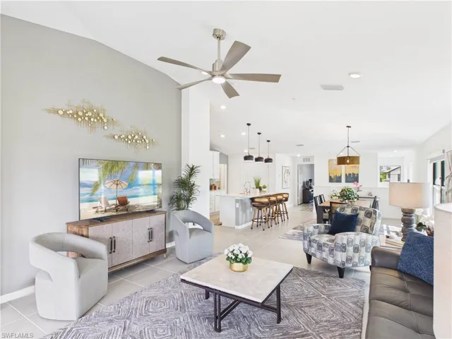 Living room featuring light tile patterned floors, ceiling fan, and vaulted ceiling