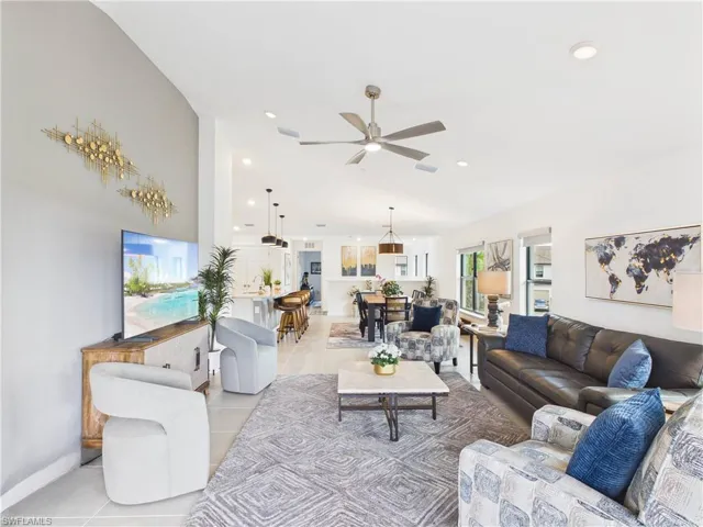 Living room featuring ceiling fan, light tile patterned floors, recessed lighting, and vaulted ceiling