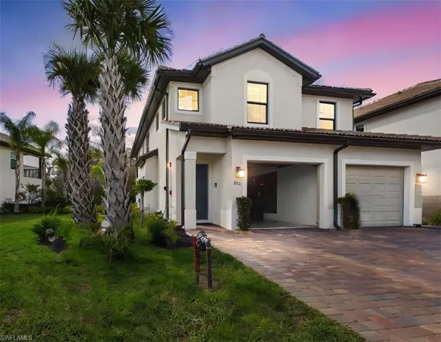 View of front facade with decorative driveway, a front yard, stucco siding, and a tile roof