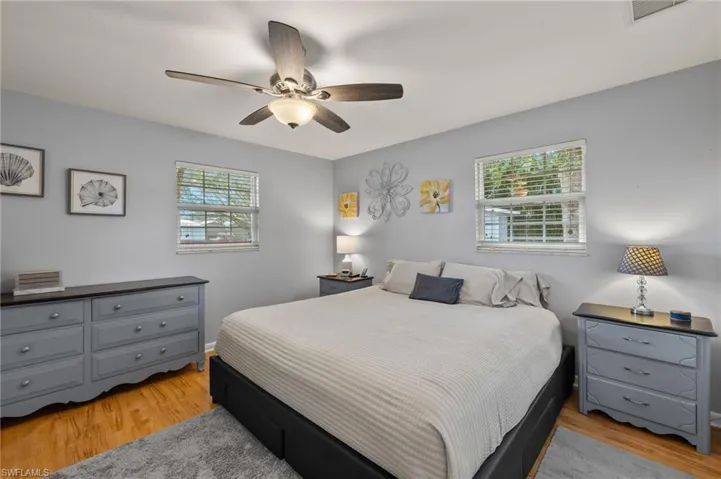 Bedroom featuring ceiling fan, multiple windows, and light hardwood / wood-style flooring