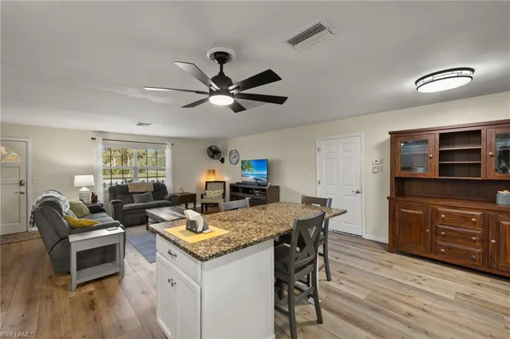 Kitchen featuring dark stone counters, a breakfast bar, light hardwood / wood-style flooring, and white cabinets