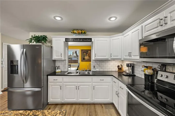 Kitchen with white cabinetry, appliances with stainless steel finishes, sink, and light hardwood / wood-style flooring