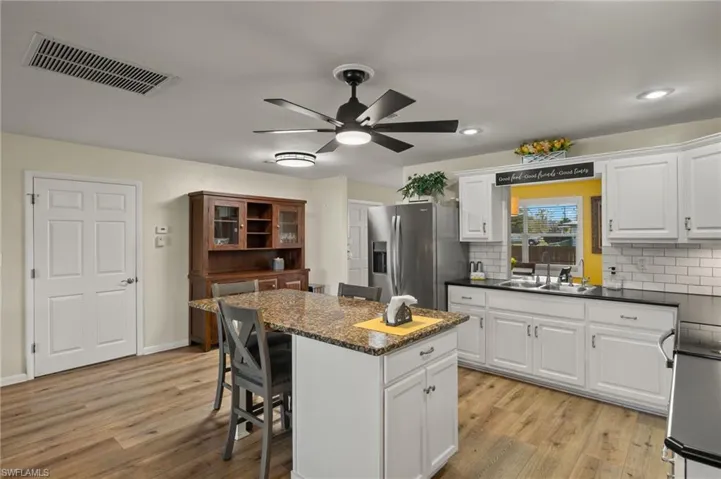 Kitchen featuring white cabinetry, stainless steel fridge, a center island, and sink