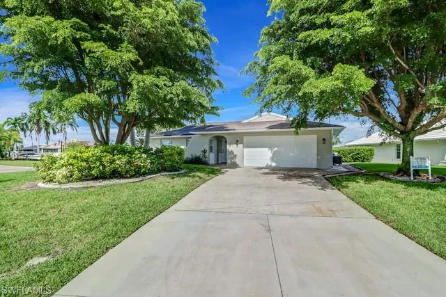Single story home featuring a garage, a front yard, driveway, and stucco siding