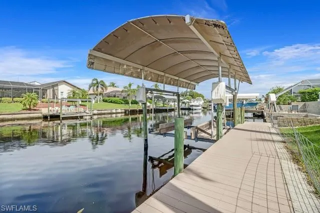 Dock with boat lift, a water view, and a residential view