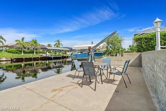 View of patio with a water view, a dock, outdoor dining area, and boat lift