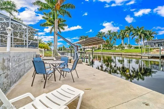 View of patio with a boat dock, boat lift, a lanai, and a water view