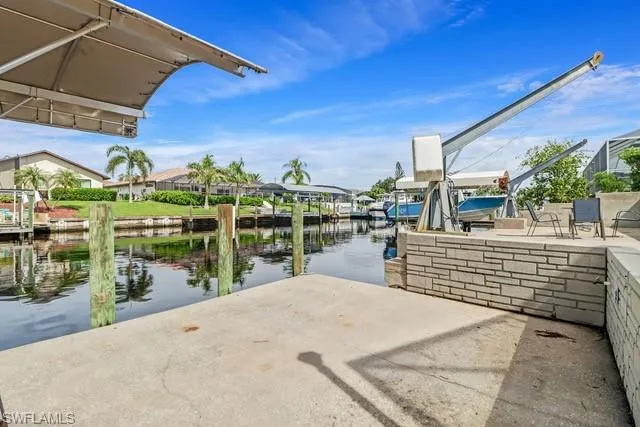 Dock featuring a water view, boat lift, a patio area, and a residential view