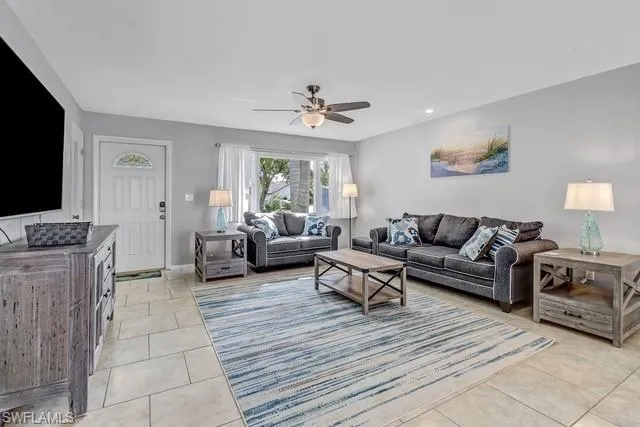 Living room with a ceiling fan, light tile patterned floors, and recessed lighting