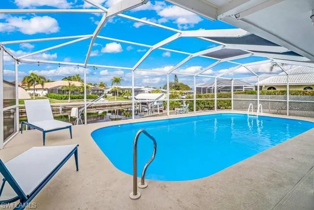 Outdoor pool featuring a sunroom, a patio area, and glass enclosure