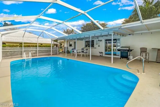 View of swimming pool featuring a sunroom, a lanai, patio surround, and a grill