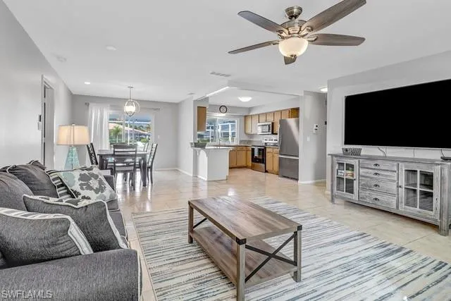 Living room with ceiling fan and light tile patterned flooring