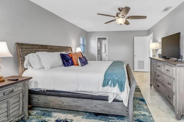 Bedroom with ensuite bath, ceiling fan, and light tile patterned floors
