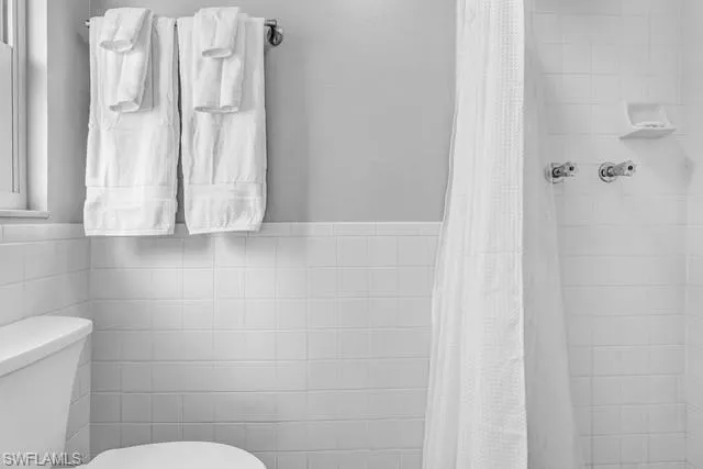 Full bath with a shower stall and tile walls