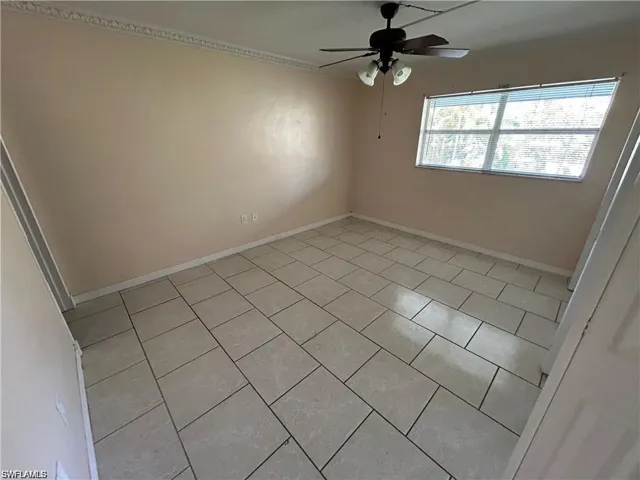 Empty room with a ceiling fan and light tile patterned floors