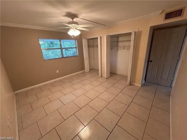 Unfurnished bedroom with two closets, ceiling fan, and light tile patterned floors
