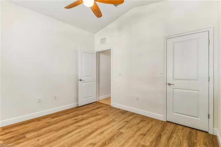 Unfurnished bedroom featuring lofted ceiling, light wood-style floors, and a ceiling fan