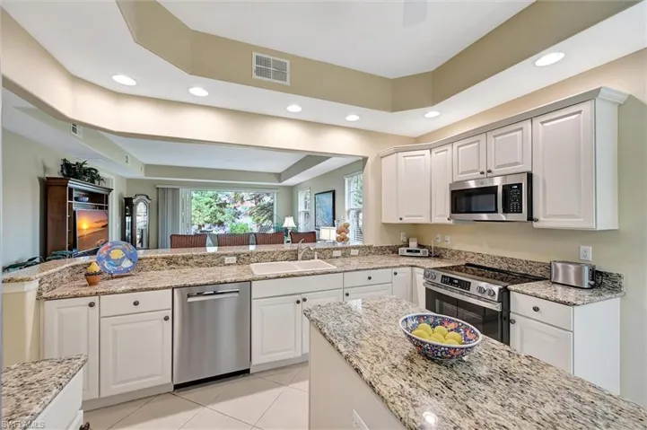 Kitchen featuring stone countertops, white cabinetry, stainless steel appliances, a center island, and recessed lighting