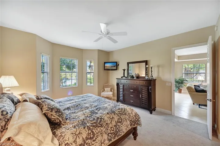 Room featuring a bay window, wall-to-wall carpeting, and a ceiling-mounted paddle fan