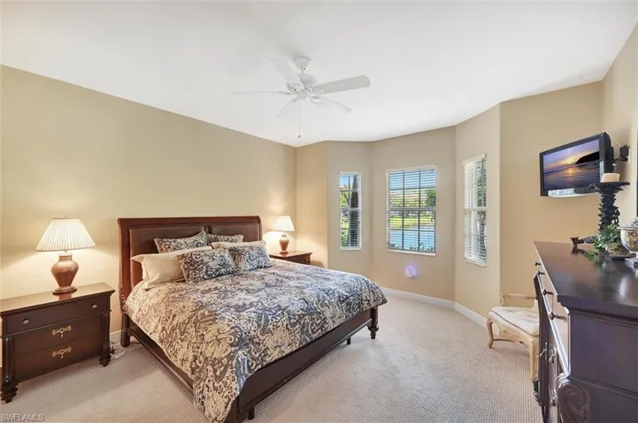 Neutral-toned interior featuring carpeting, a multi-paneled bay window, and a ceiling fan