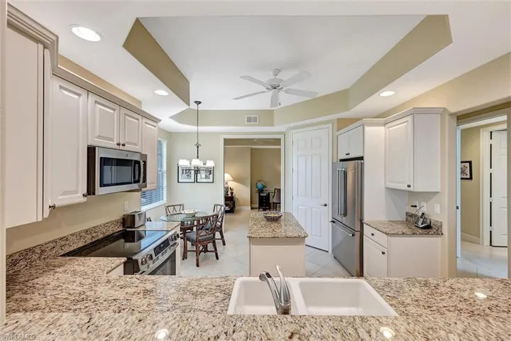 Kitchen featuring stone countertops, white shaker-style cabinetry, stainless steel appliances, a central island, and recessed ceiling lighting