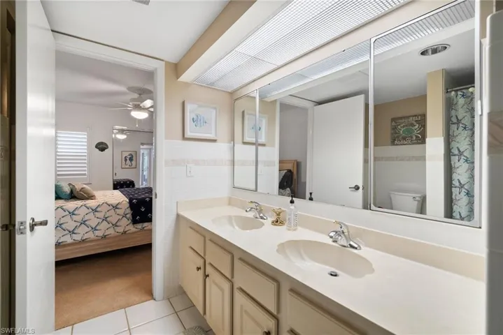 Bathroom featuring ceiling fan, vanity, toilet, tile walls, and tile patterned flooring
