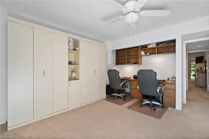 Carpeted home office with ceiling fan and built in desk