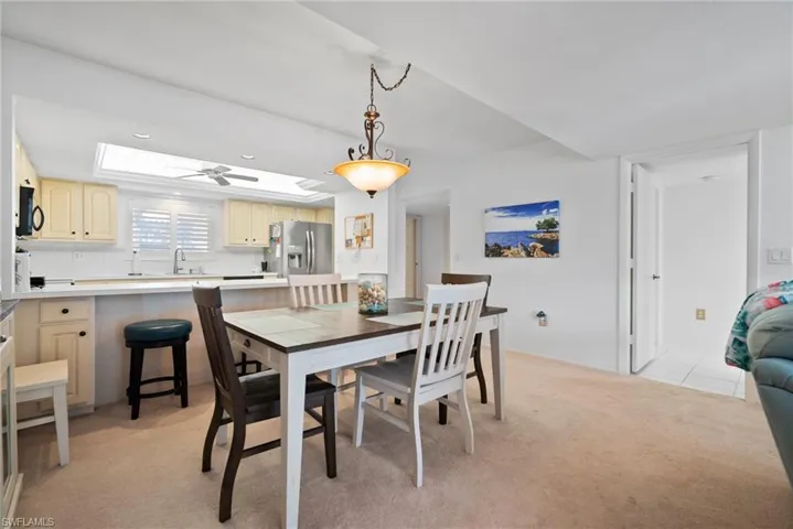 Dining room with ceiling fan, light colored carpet, a skylight, and sink