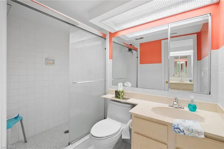 Bathroom featuring walk in shower, vanity, and toilet