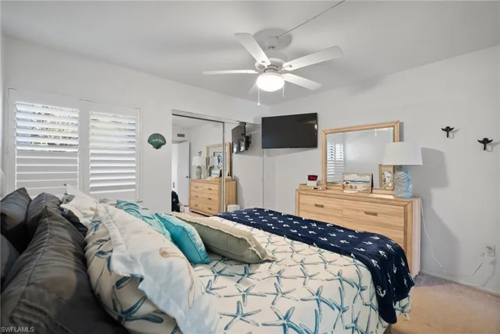 Carpeted bedroom with ceiling fan and a closet