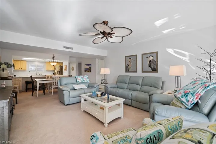 Living room with ceiling fan, light colored carpet, and sink