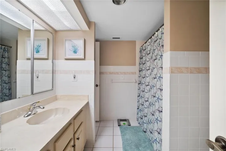 Bathroom with tile walls, tile patterned floors, vanity, and curtained shower