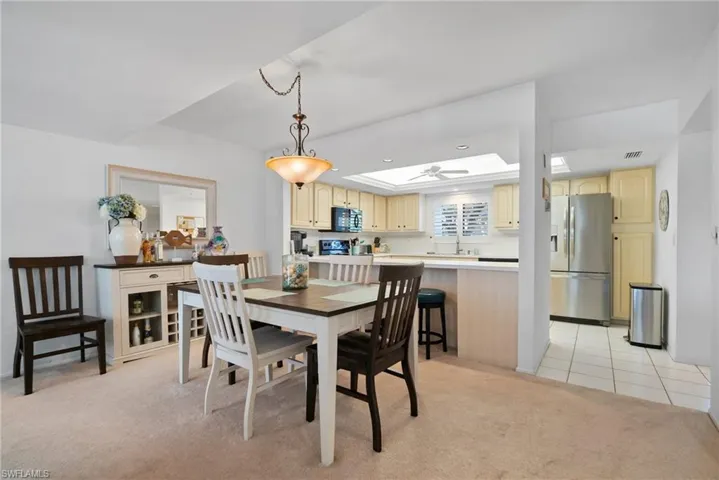 Carpeted dining area featuring a skylight and a raised ceiling