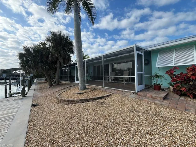 VIEW OF REAR OF HOME SHOWING SCREENED LANAI.  BAHAMA SHUTTER OVER OWNER'S SUITE WINDOW.  ZEROSCAPE LANDSCAPING.
